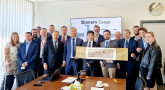 Grupa ludzi trzymająca długi prostokątny obraz na płótnie