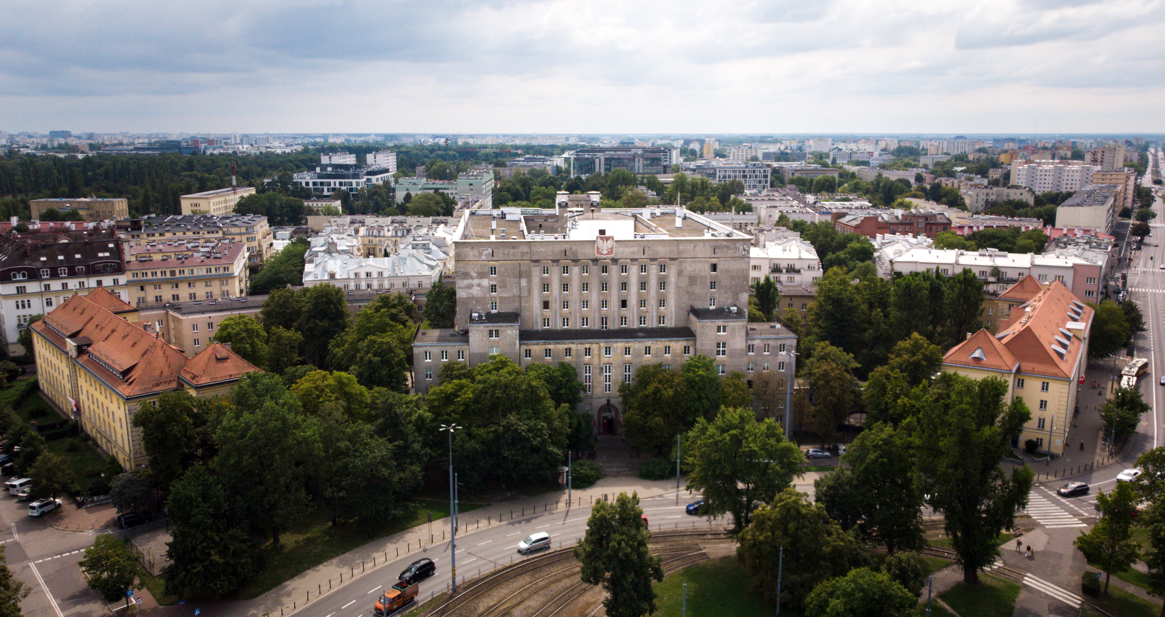 Duży gmach z godłem otoczony zielenią.