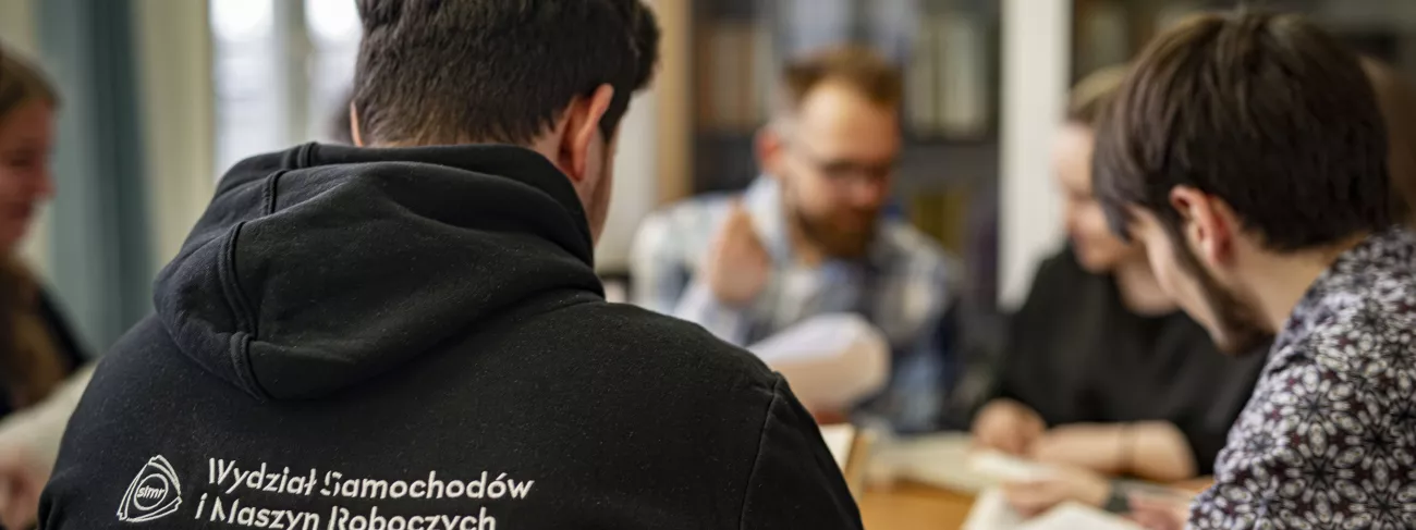 Grupa młodych osób siedząca wokół stołu.