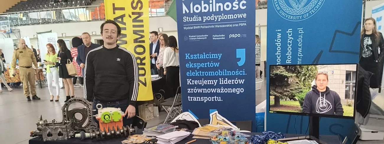 Student stojący na stoisku promocyjnym Uczelni