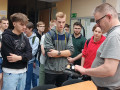 Nauczyciel pokazujący uczniom części samochodowe.